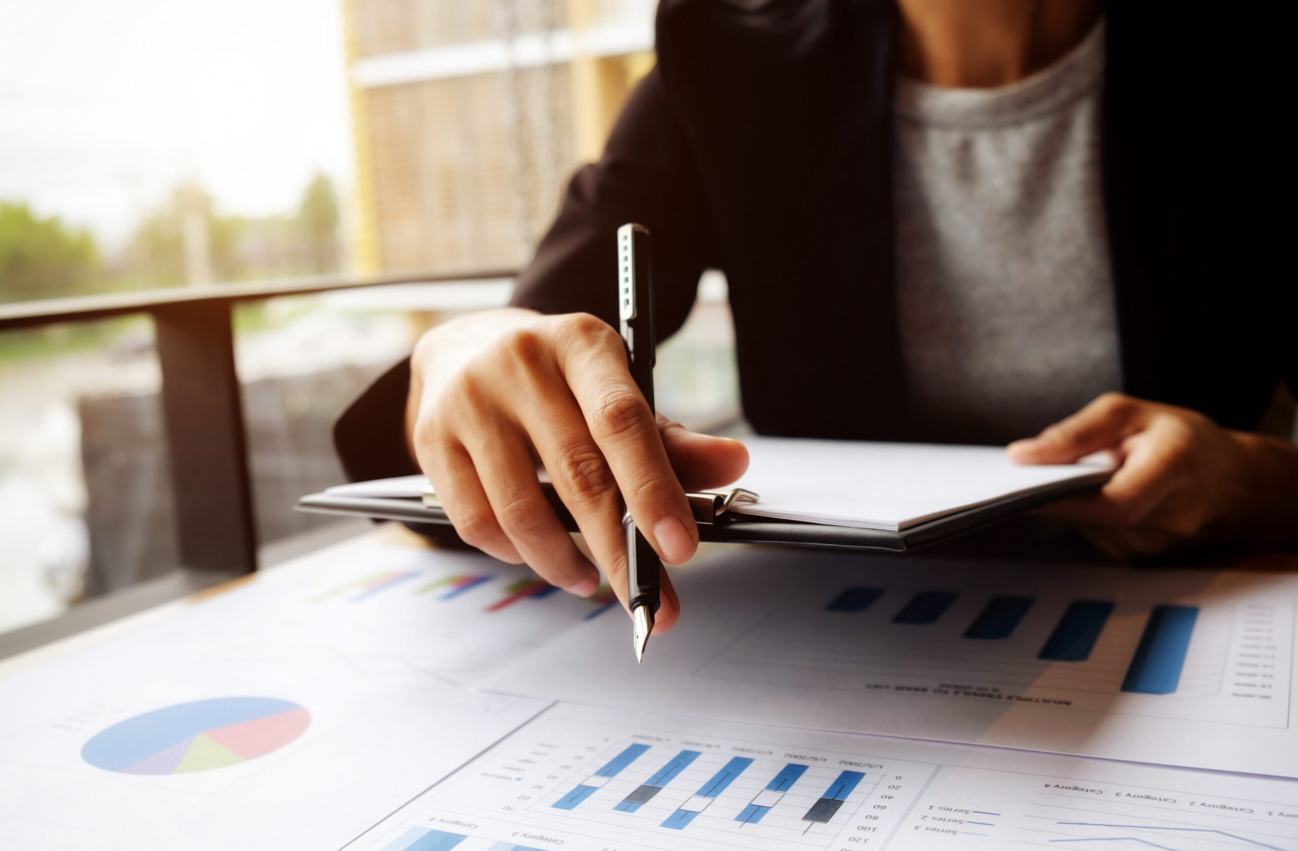 female manager putting his ideas and writing business plan at workplace,woman holding pens and papers, making notes in documents, on the table in office,vintage color,morning light ,selective focus.