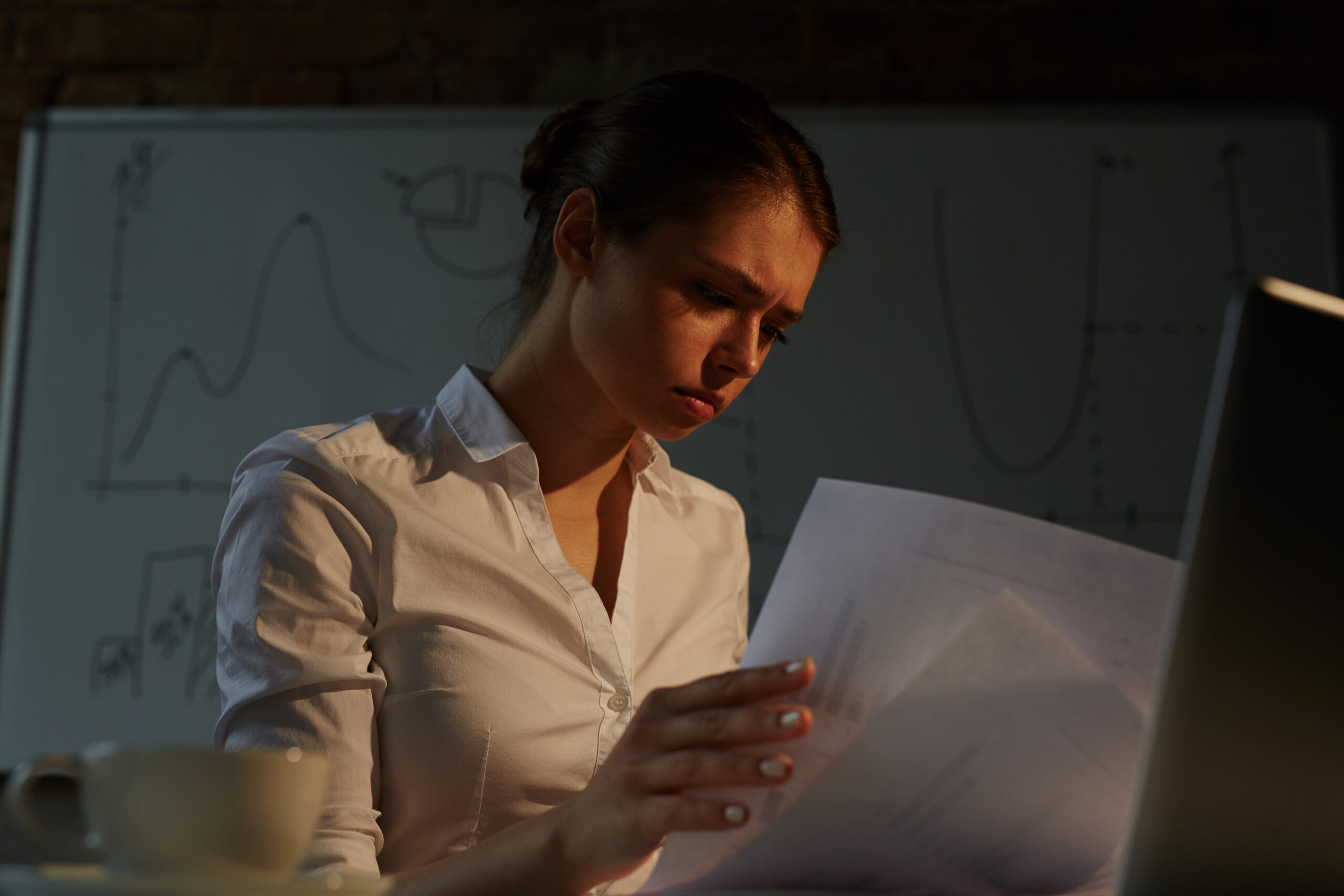 Busy woman looking through financial papers in office at night
